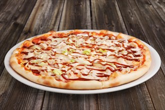 Pizza with chicken barbecue on wooden table