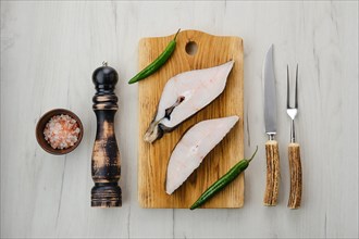 Top view of raw fresh halibut steak on wooden cutting board with spices