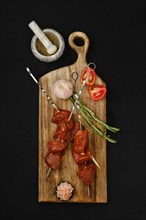 Top view of skewers with marinated raw pork meat on dark background