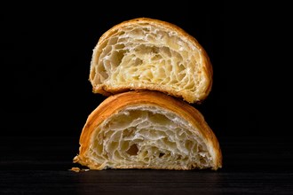 Croissant cut in a half on black background