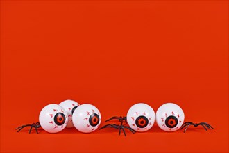 Spooky Halloween eyeballs and spiders on red background with copy space