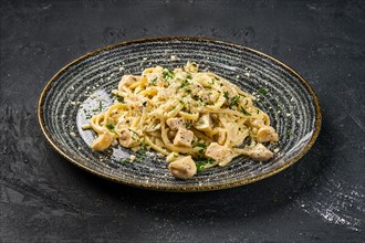 Pasta with mushrooms and chicken on black background