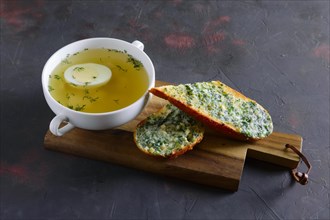 Clear chicken broth with egg served with toasts