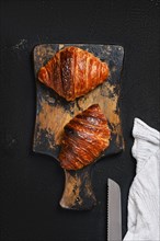 Top view of crispy croissant on wooden serving board
