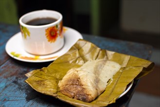 View of a stuffed tamale with a cup of coffee served on a wooden table