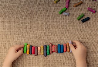 Toddlers hand putting crayons in line on canvas