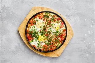 Top view of eggs with bell pepper and tomato baked in oven in cast-iron skillet