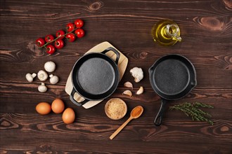 Cast iron skillets and spices on dark wooden culinary background