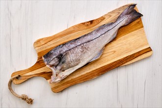Top view of raw fresh haddock carcass on wooden cutting board