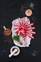 Fresh raw rack of lamb on wrapping paper with herbs and seasoning