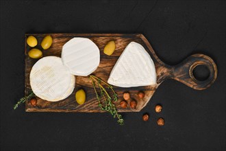 Top view of cheese platter. Assortment of brie and camembert cheese on wooden cutting board