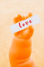 Toy doll hand holding paper with LOVE wording