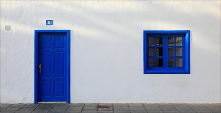 Typical architecture with whitewashed wall and blue windows