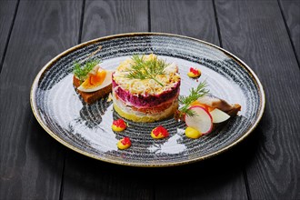 Herring layered salad decorated with a quarter of a boiled egg and a piece of herring