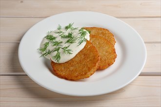 Draniki with sour cream on wooden table