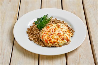 Chopped pork meat baked with cheese and tomato served with buckwheat porridge