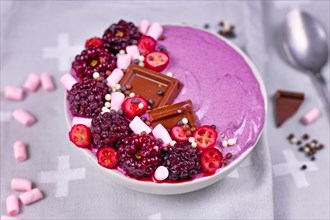 Pink smoothie bowl decorated with healthy red raspberry and cranberry fruits