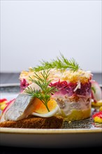 Close up view of herring layered salad decorated with a quarter of a boiled egg and a piece of herring