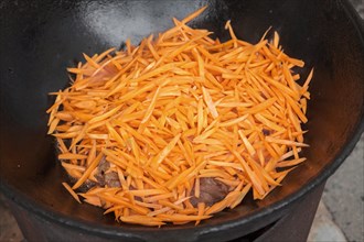 Meat orange carrot and onions in cauldron. The making of pilaf