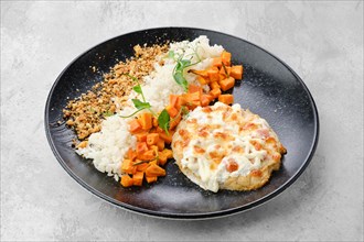Chopped pork cutlet baked with ham and cheese served with carrot and rice on a plate