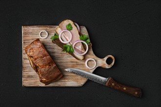 Overhead view of rural sandwich with smoked bacon with brown bread on wooden cutting board