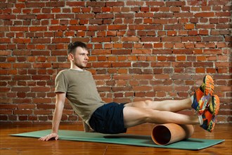 Athletic man doing exercises for the balance on rubber ball with gymnastic stick. Fitness workout