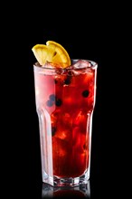 Cold lemonade with orange juice and black currant isolated on black background