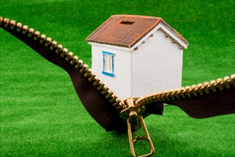 House model through a zipper on green grass