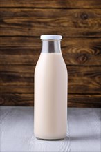 Bottle of soy milk on white table over dark wooden background