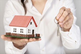 Female holding a toy model house and keys