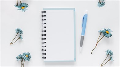 Notepad pen near blue chamomile flowers