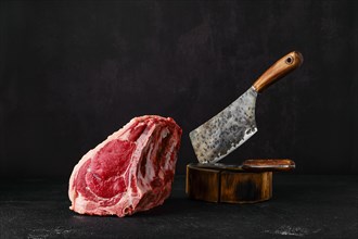 Raw rib-eye steak bone in on dark background