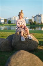 Cute little child sitting on stone in sunset time