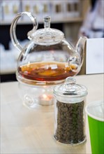 Herbal tea brewed in glass teapot and tea plant in a bottle