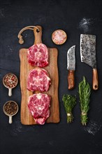 Fresh raw lamb neck on wooden cutting board with herbs and seasoning