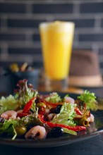 Selective focus photo of spanish salad with shrimps and glass of granisado on background