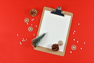 Christmas flat lay with empty clipboard surrounded by small Christmas trees