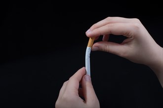Hand is breaking a cigarette on a black background