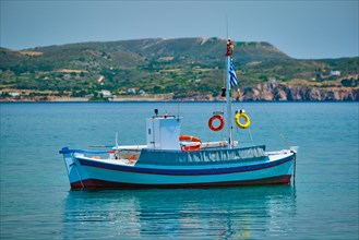 Greek fishing boat moored in blue waters of Aegean sea in harbor of near Milos island