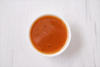 Overhead view of small bowl with spicy orange sauce for poultry