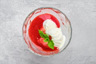 Top view of ice cream with strawberry jam in a glass bowl