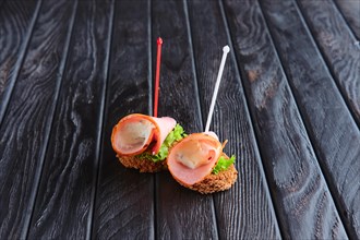 Appetizer for reception. Brown bread with slice of ham stuffed with soft cheese on skewer