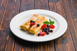 Plate with thin pancakes stuffed with curd and served with berry jam