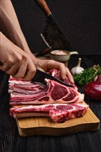 Man cutting rack of lamb on wooden board. Preparing fresh meat for cooking