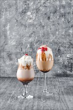 Two glasses with latte drink with whipped cream and cherry