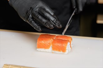Chef cuts salmon rolls with knife