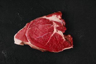 Overhead view of raw top round roast beef steak on dark background