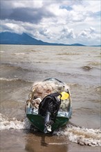 Fishing boat on the shore of a lake. A fishing boat on the shore of a lake with volcanoes in the background. A fishing boat on a lake in Nicaragua. Concept of fishing boats parked at the seaside