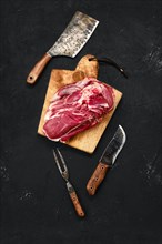 Overhead view of raw lamb shoulder without bone on wooden cutting board