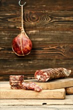 Smoked dried pork sausage cut on slices on wooden cutting board